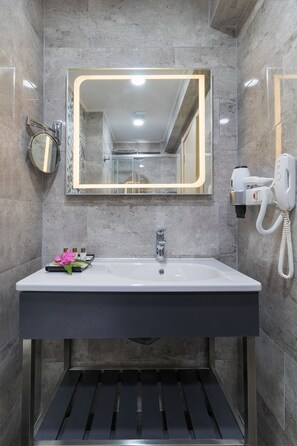 A modern bathroom with a large mirror, a sink, and a hairdryer mounted on the wall. - Amossia Elit Butik Otel (Marmaris)