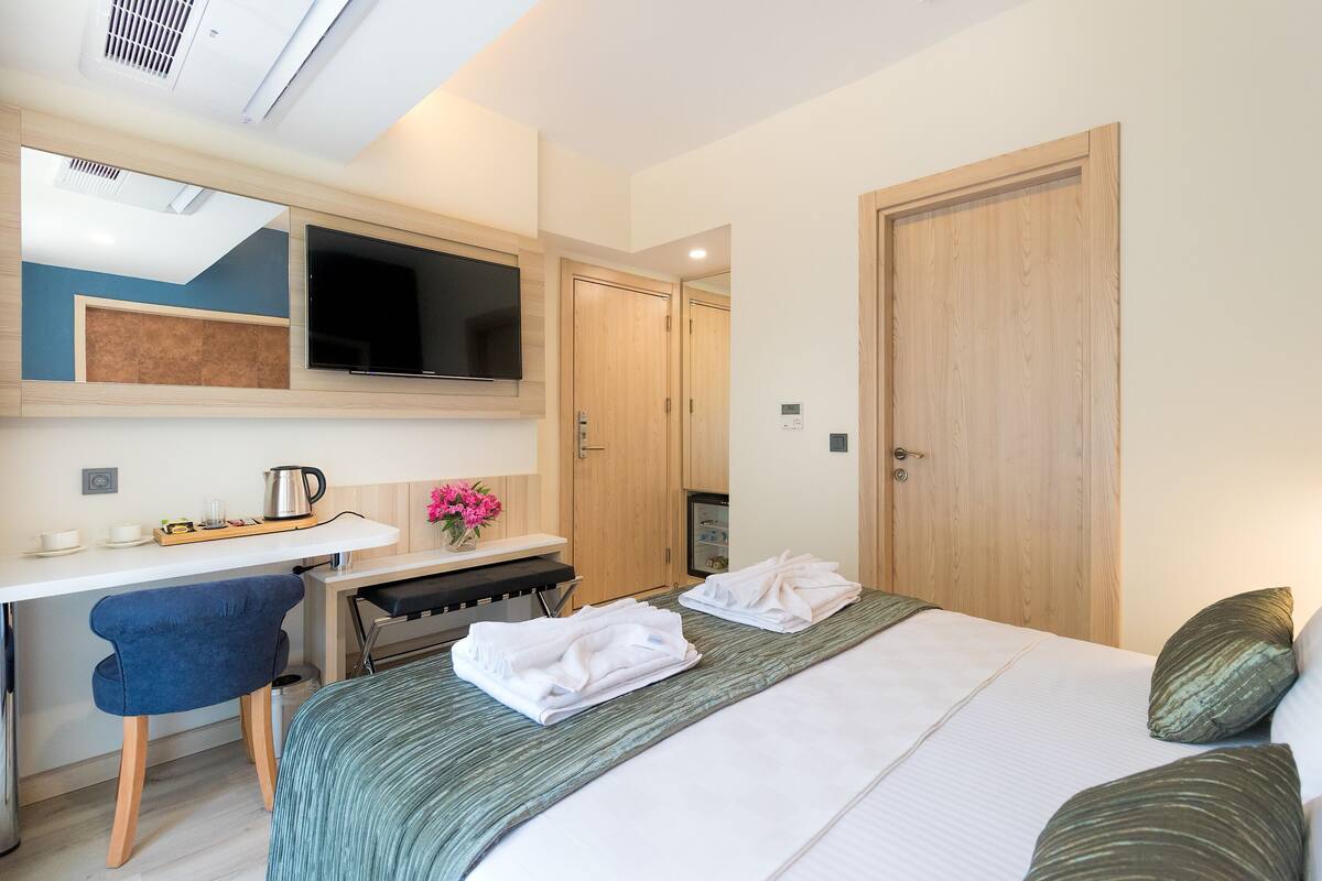 Ein Hotelzimmer mit Bett, Schreibtisch mit Stuhl, Fernseher und Kleiderschrank.