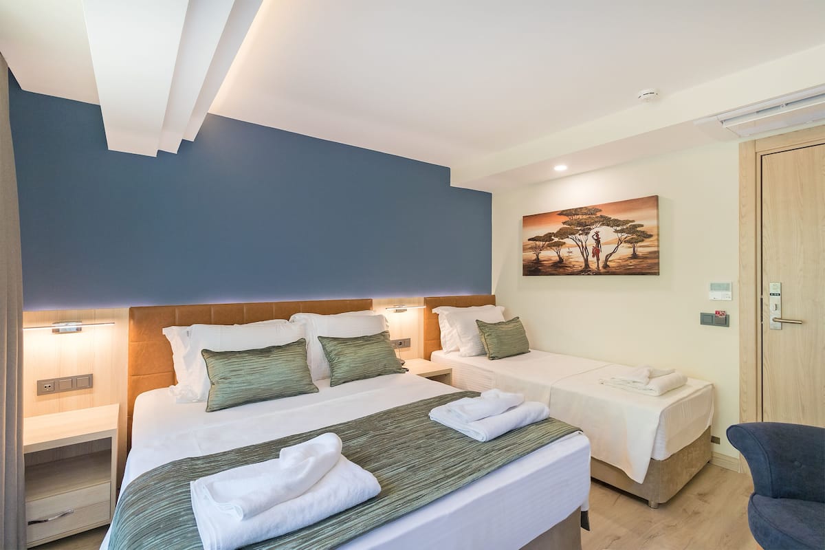 Ein Hotelzimmer mit zwei Betten, einem Bild an der Wand und einer Holztür.