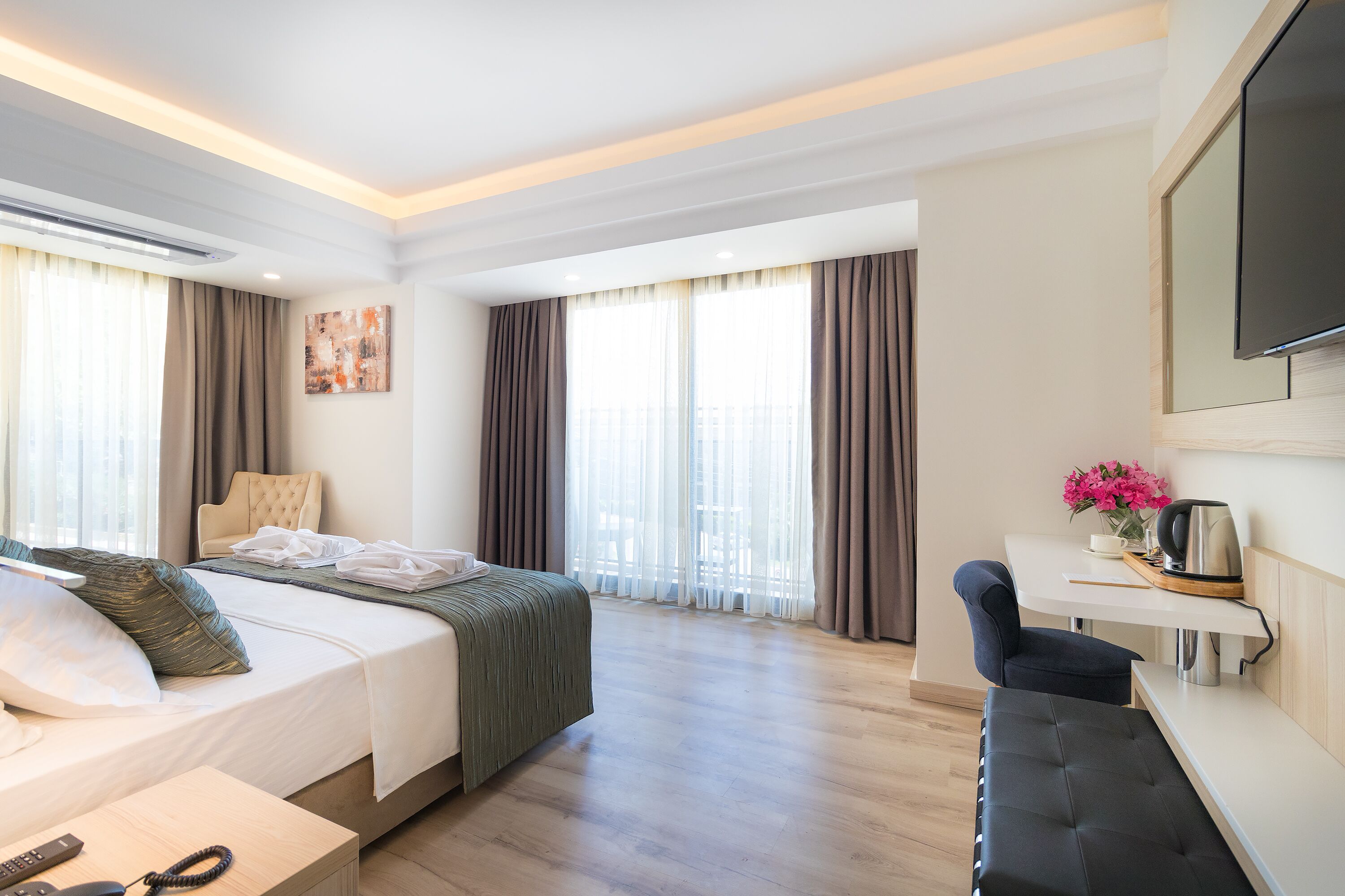 Une chambre d’hôtel moderne équipée d’un lit, d’une table de chevet et d’un petit bureau avec une chaise.