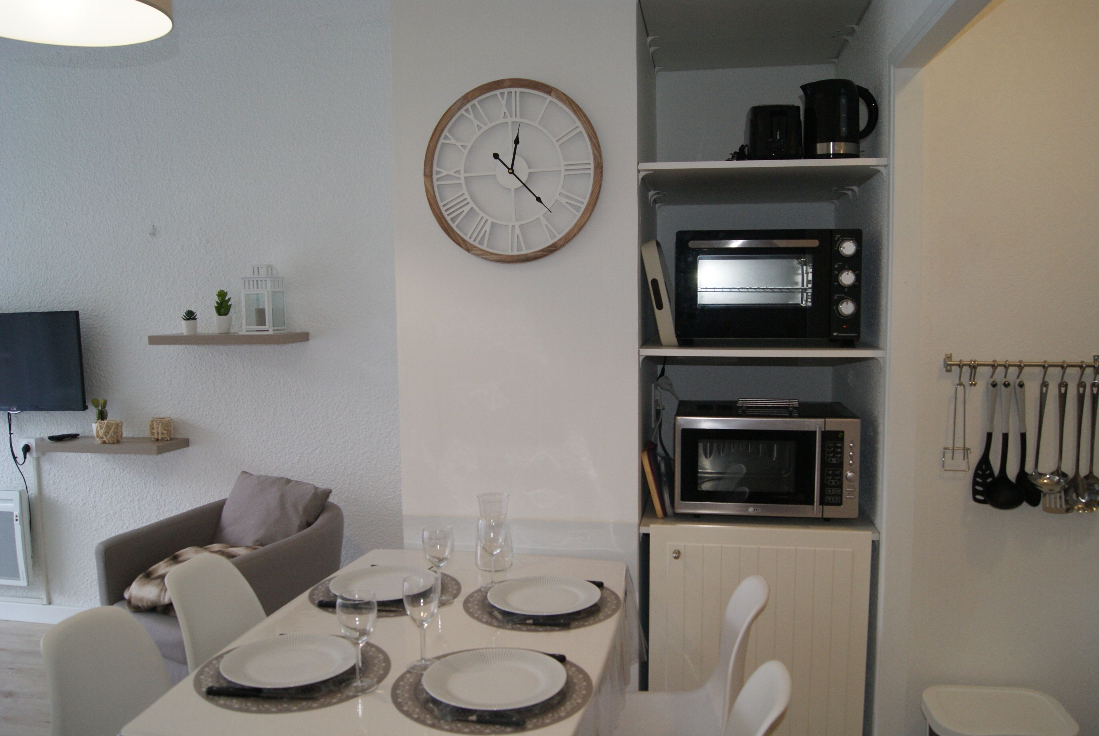 A modern kitchen with a built-in microwave, a clock, and a dining area with a table set for two.