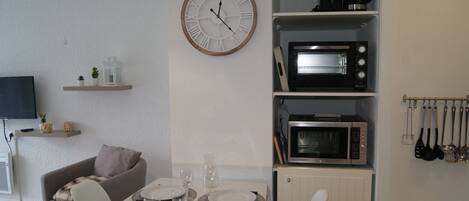 A modern kitchen with a built-in microwave, a clock, and a dining area with a table set for two.