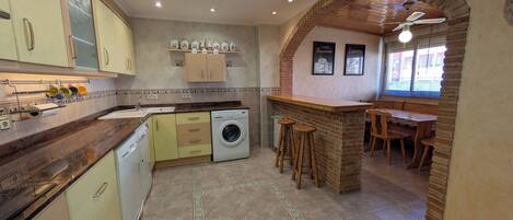 A kitchen with a washing machine, a coffee bar, and a dining area with a brick archway.