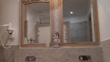 A bathroom with two sinks, a mirror, a wall-mounted phone, and a decorative statue.