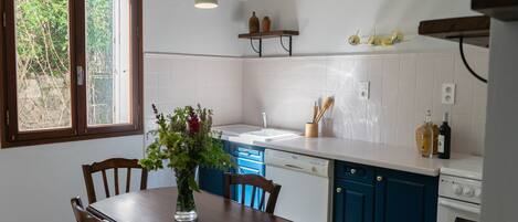 Una cocina con una mesa de comedor, sillas, lavavajillas y estufa.