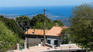 A stone building with a tiled roof, surrounded by greenery and overlooking a coastal landscape. - Family house l'Ospedale - Porto-Vecchio (Porto-Vecchio)