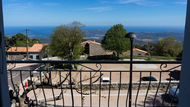 A balcony with a view of a coastal town, stone buildings, and a clear blue sky. - Family house l'Ospedale - Porto-Vecchio (Porto-Vecchio)