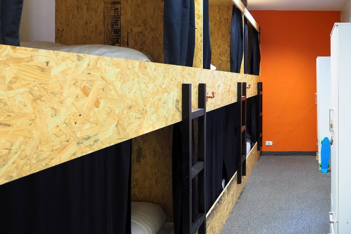 A bunk bed room with a wooden headboard, black curtains, and an orange wall.