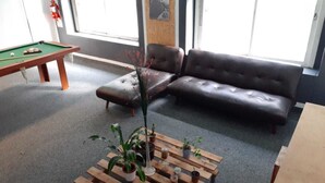 A room with a pool table, a sofa, and a coffee table with potted plants. - La Bamba Student Hostel (Buenos Aires)