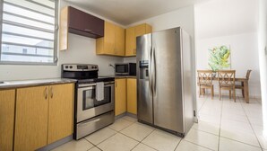A modern kitchen with stainless steel appliances, wooden cabinets, and a dining area with a table and chairs. - Private pool, Oceanview, Centrally located! (Puerto)