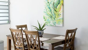 A dining table with four wooden chairs, a potted plant, and a large abstract painting on the wall. - Private pool, Oceanview, Centrally located! (Puerto)