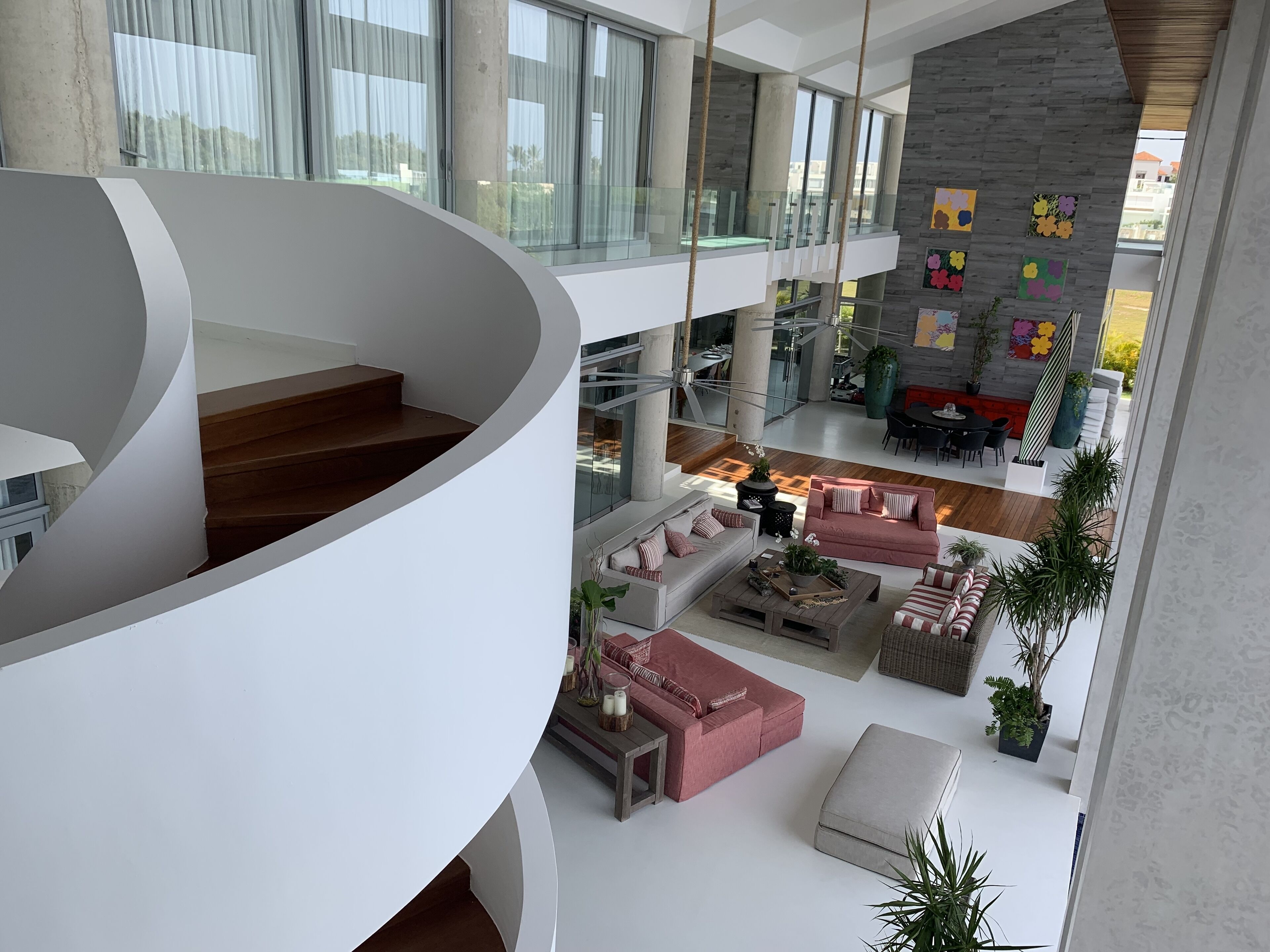 A modern interior with a curved staircase, a dining area, and a living space with sofas and a coffee table.
