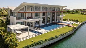 Una moderna casa a due piani con una grande piscina, un patio coperto e vista su un corpo d'acqua.