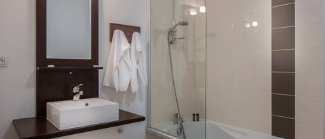 A bathroom with a white sink, a mirror, a glass-enclosed shower, and a bathtub.