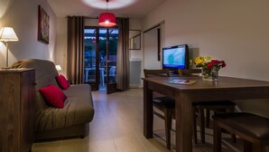 Ein gemütliches Zimmer mit einer Couch, einem Esstisch und einem Fernseher.