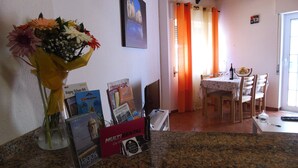Een keuken met granieten aanrecht, een eettafel met stoelen, een vaas met bloemen en een lijst met foto aan de muur.