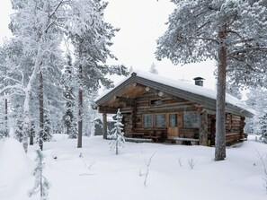 Une cabane en rondins entourée d’arbres couverts de neige.