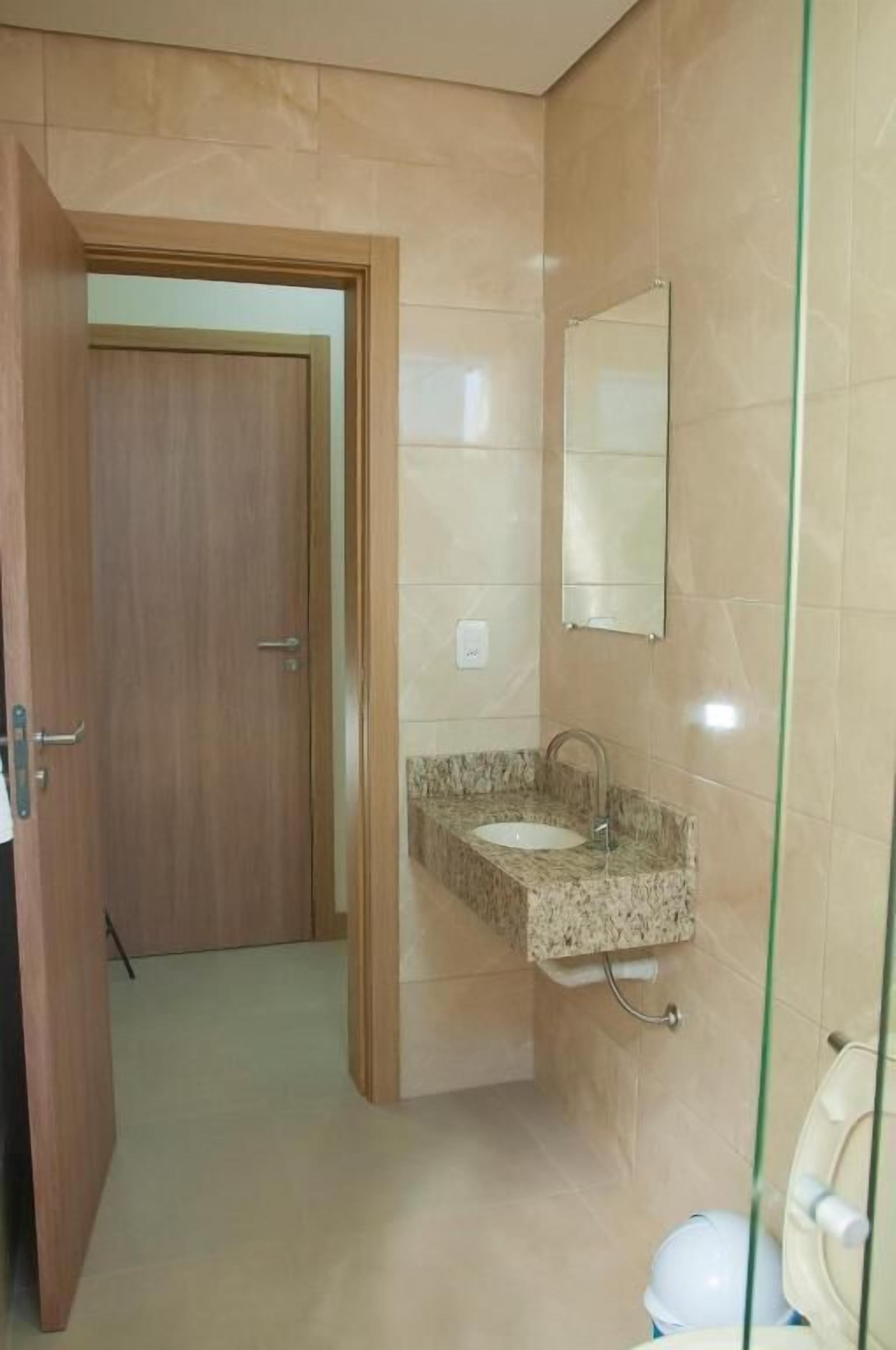 Un baño con lavamanos de mármol, un espejo y un inodoro.