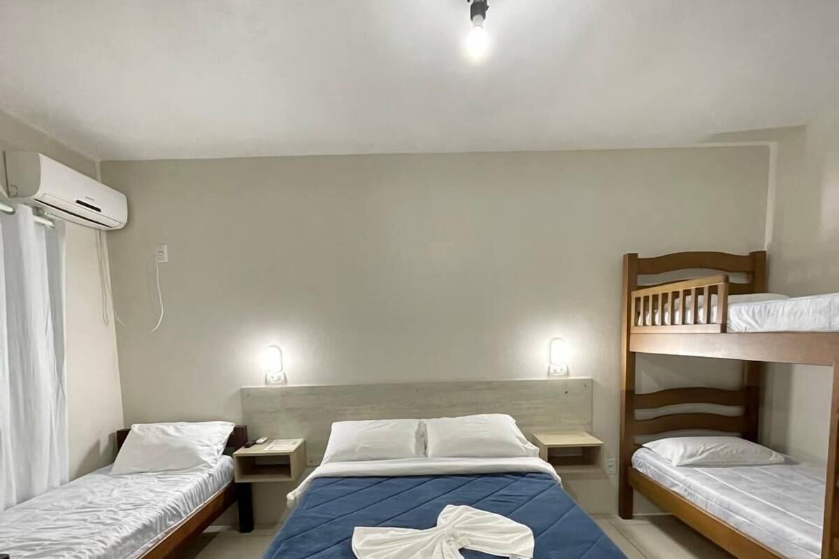 Une chambre avec deux lits simples, un lit superposé, un bureau et une table de chevet.