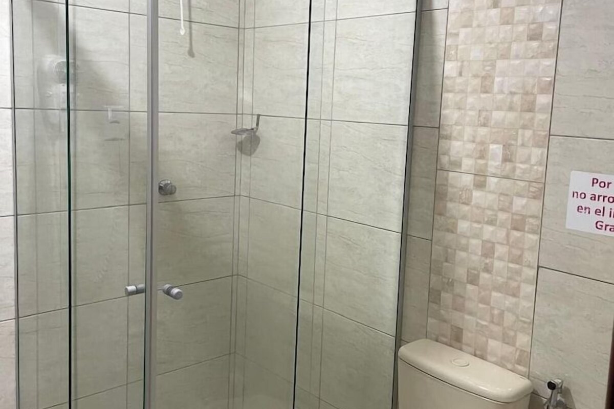 Een douchecabine met glazen wanden en een aangrenzend toilet.
