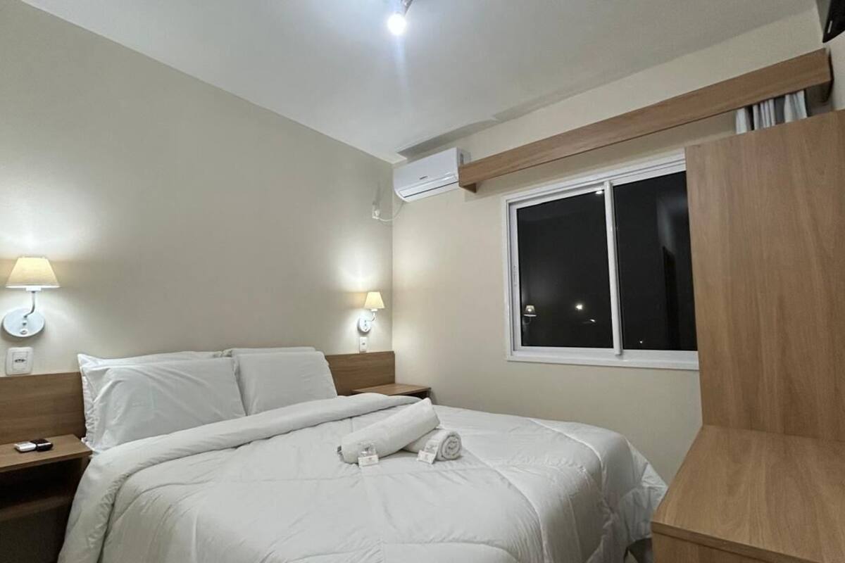 Une chambre d’hôtel avec un lit, des lampes de chevet, une table de nuit et une fenêtre.