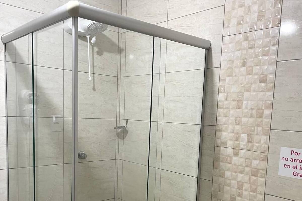 Une cabine de douche fermée par des parois en verre, avec des toilettes à côté.