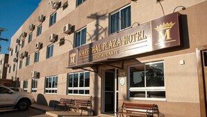 Un hotel con un letrero que dice "Marechal Plaza Hotel Restaurante" y un símbolo de corona. Hay unidades de aire acondicionado en el edificio, y un coche estacionado frente a él.