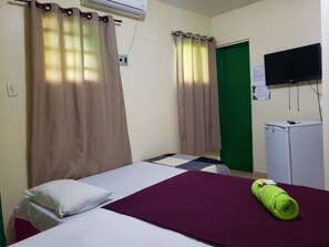 A hotel room with a bed, a desk with a computer, a green door, and an air conditioner on the wall. - Pousada Catamarã Praia de Pajuçara (Maceió)