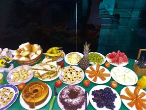A buffet table with various food items including sandwiches, fruits, and desserts. - Pousada Catamarã Praia de Pajuçara (Maceió)