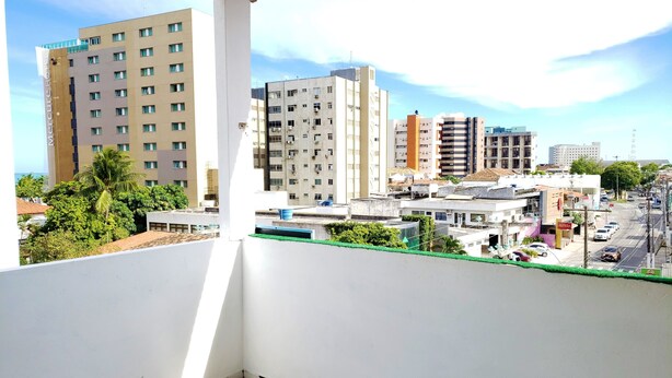 A balcony with a view of a cityscape, including a hotel and various buildings. - Pousada Catamarã Praia de Pajuçara (Maceió)