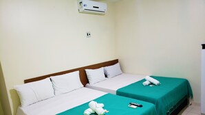 A hotel room with two single beds, each with a green bedspread and white pillows. There is a white air conditioning unit on the wall above the beds. - Pousada Catamarã Praia de Pajuçara (Maceió)