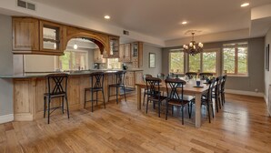 Una cocina amplia con una isla central, armarios de madera y un comedor con una mesa grande y sillas.