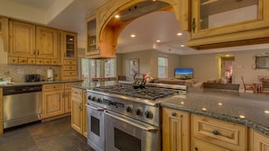 Una cocina amplia con gabinetes de madera, estufa de acero inoxidable y encimeras de granito.