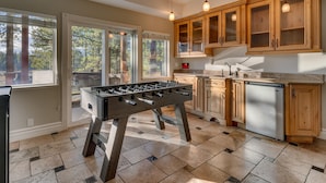 Una cocina con armarios de madera, lavavajillas de acero inoxidable y una mesa de fútbol.