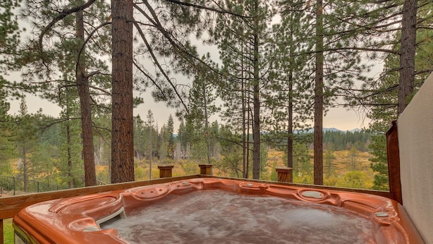 Un jacuzzi en una terraza de madera con vistas a un bosque.