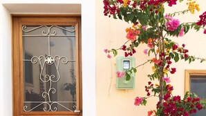 Une porte en bois ornée d’un panneau de verre décoratif et un grand pot en terre cuite rempli de fleurs aux couleurs vives, le tout posé sur un tapis à motifs.