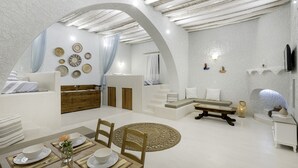 Un vaste espace de vie doté d’un haut plafond, d’un banc en bois et d’une table à manger pour quatre personnes.