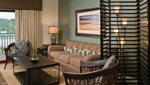 Un salon confortable avec un canapé, deux fauteuils, une table basse, une lampe et un tableau encadré au mur.