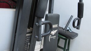 A gym with a bench, weight machine, and a wall-mounted rack.