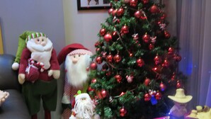 A Christmas tree with red ornaments, a Santa Claus figure, and a reindeer figure.