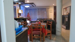 A dining area with a Christmas tree, wooden chairs, and a table set for four.