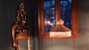 A room with a dark blue wall, a wooden-framed window, and a hanging light fixture. - Al Teatro Italia (Venice)