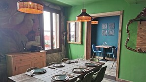 A dining area with a wooden table set for six, green chairs, and hanging wicker lamps. - Al Teatro Italia (Venice)