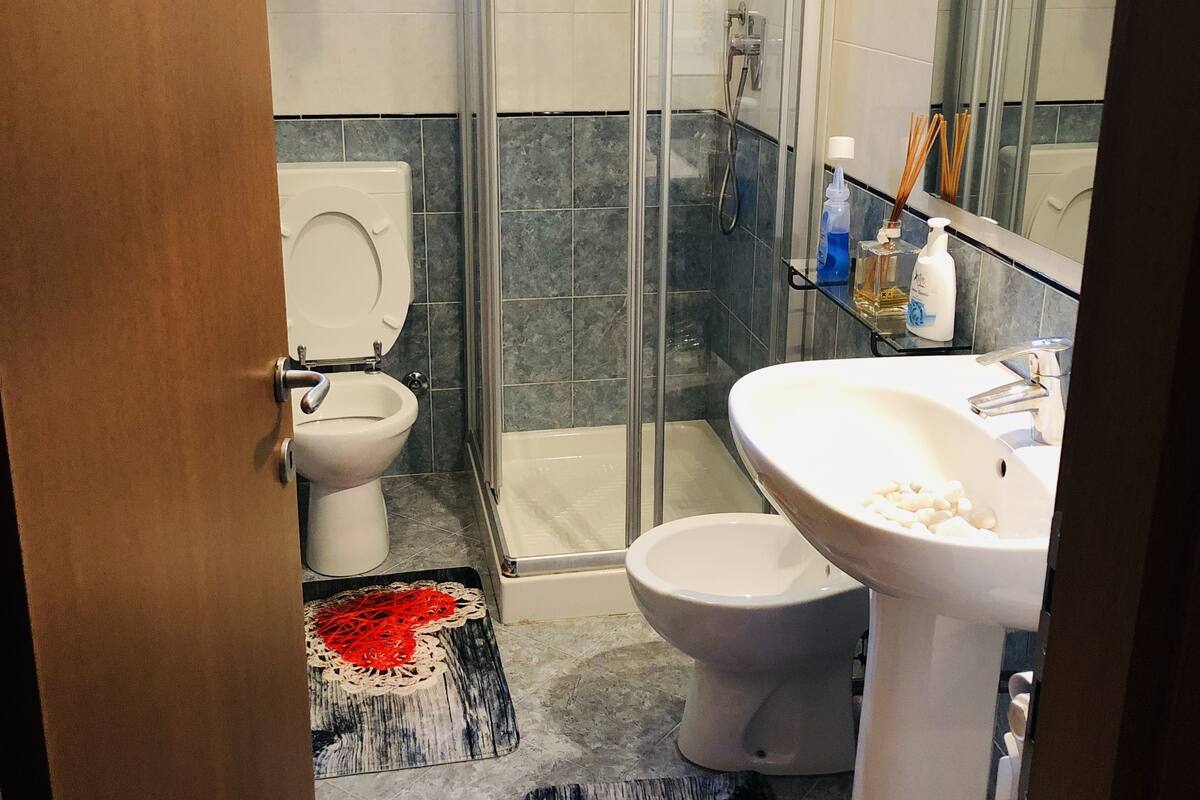A bathroom with a glass-enclosed shower, a toilet, a sink, and a mirror.