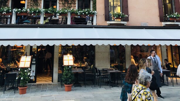 A building with multiple balconies, some with potted plants. There are outdoor seating areas with tables and chairs. - Al Teatro Italia (Venice)