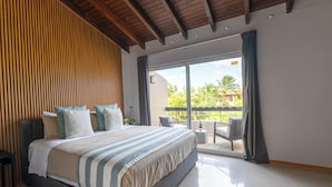 A modern hotel room with a large bed, a wooden slatted wall, a balcony with a view of palm trees, and a tiled floor. - Eagle beach walking distance Townhouse (Oranjestad-West)