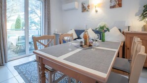 A dining area with a table set for two, a sofa, and a view of a balcony. - Résidence Les Jardins d'Azur by Interhome (Saint-Raphaël)