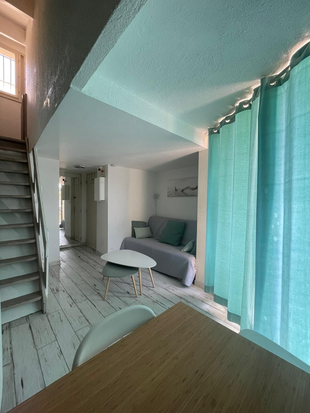 Un salon avec un canapé, une table et un escalier.