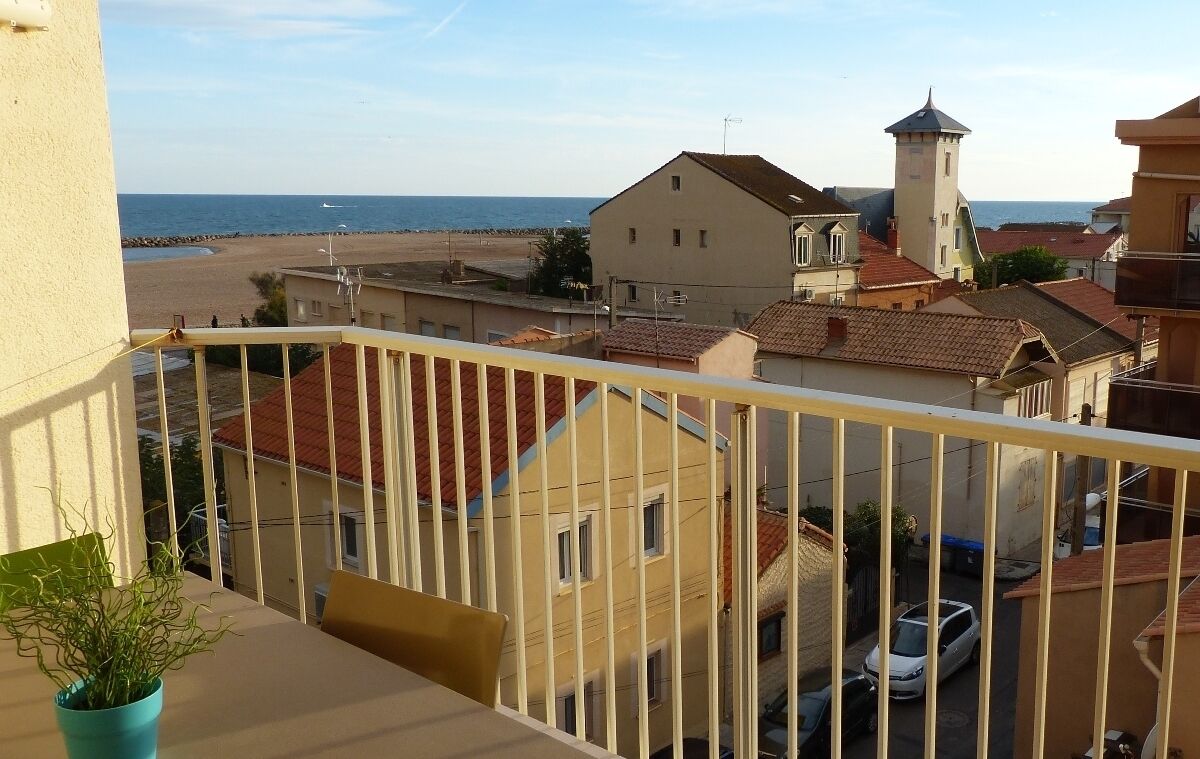 Un balcon donnant sur une plage et des immeubles.