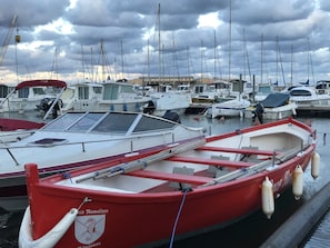 A marina with several boats docked, including a red boat with a logo and a white boat with a cabin.
